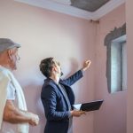 Professional discussing property damage assessment with client in a residential setting, highlighting claims adjustment process for insurance.